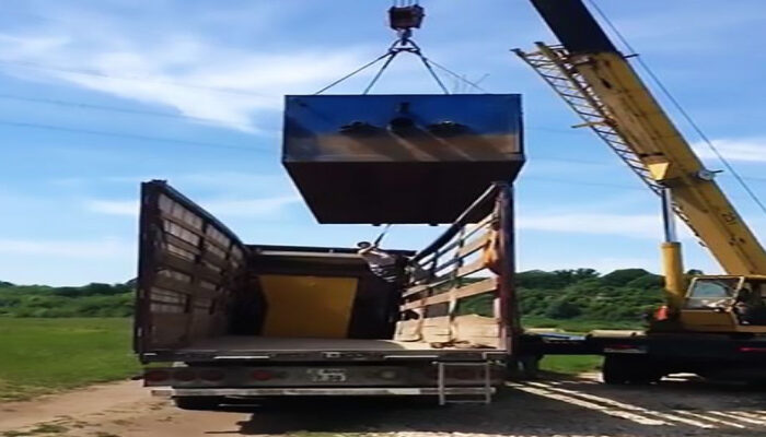 a crane pull down heavy box on man standing truck climbing box